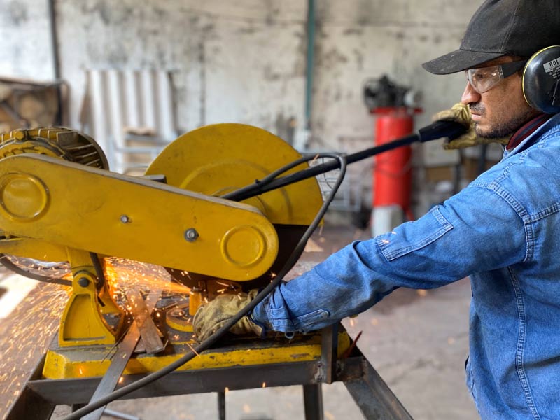Operador de Home Athletic realizando corte de metal durante proceso de Fabricación de Máquinas para Gimnasio