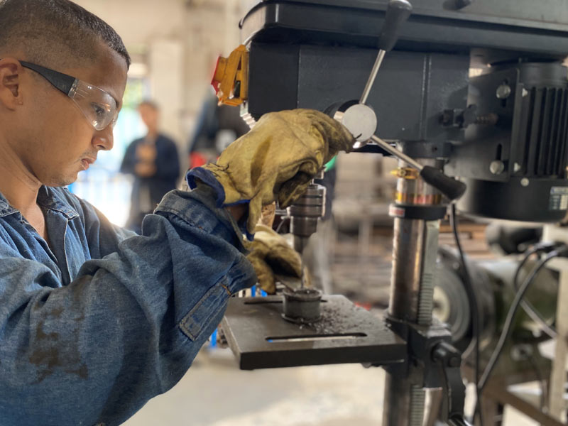 Operador de Home Athletic realizando perforación de piezas de metal durante proceso de Fabricación de Máquinas para Gimnasio