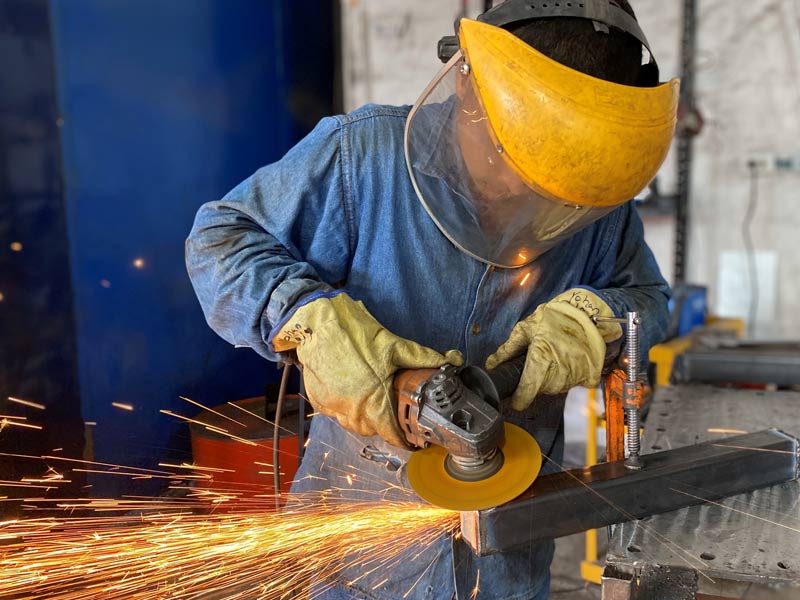 Operador de Home Athletic realizando pulido de piezas de metal durante proceso de Fabricación de Máquinas para Gimnasio