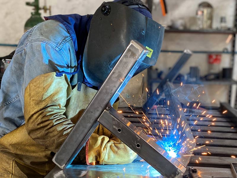Operador de Home Athletic realizando soldadura en mig de piezas de metal durante proceso de Fabricación de Máquinas para Gimnasio